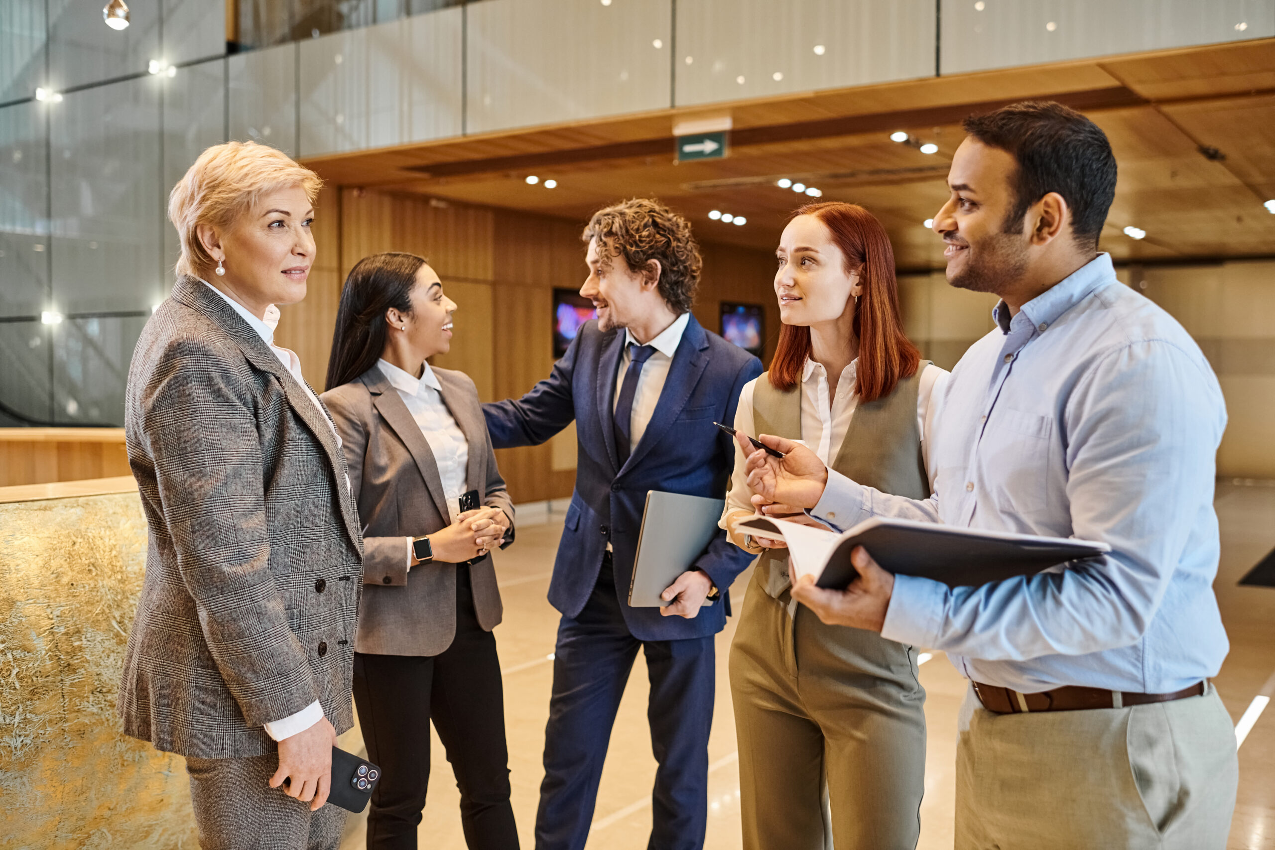 Diverse business team standing together in a lobby, discussing and collaborating.